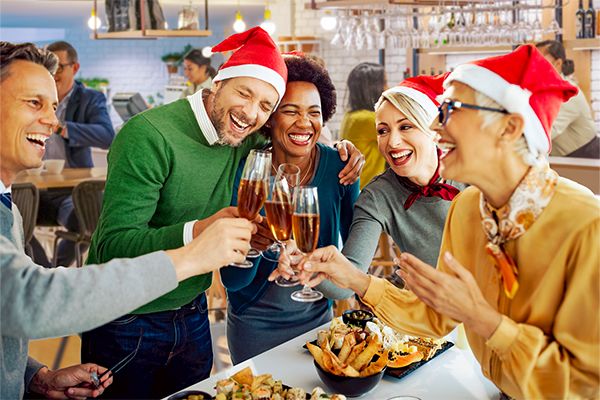 A Group Of People Wearing Santa Hats And Holding Glasses Of Beer